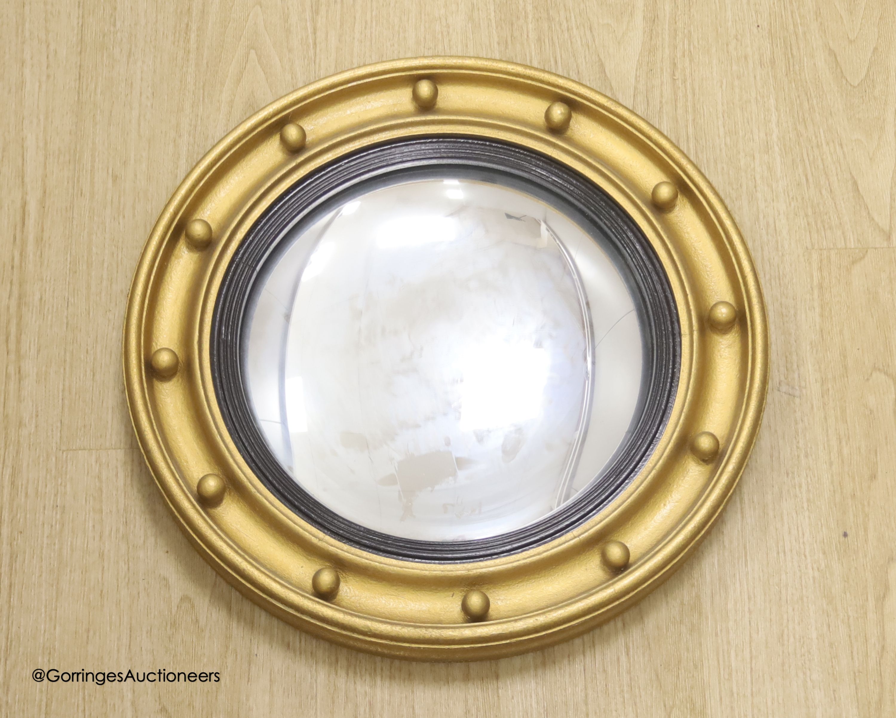 A circular gilt convex wall mirror, overall diameter 85cm